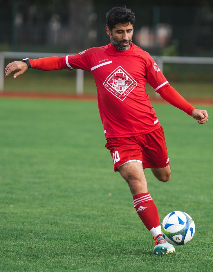 Man in Red Soccer Jersey Kicking Soccer Ball